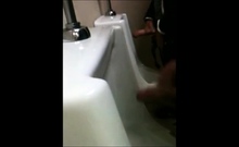 two slim dicks getting wanked at the urinals