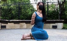 asian in blue dress tied in public takes a walk